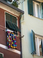  A colourful quilt hangs out of the window in Vernazza